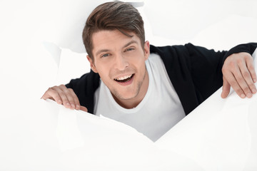 young businessman breaking through a paper wall.