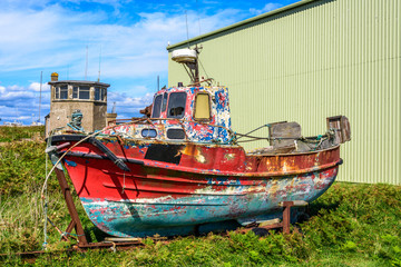 Fototapeta na wymiar Colorful rusty boat in front of a factory hall, Ireland