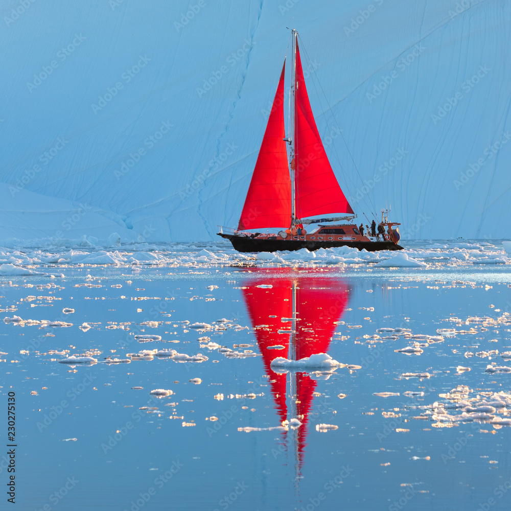 Wall mural beautiful red sailboat in the arctic next to a massive iceberg showing the scale. ilulissat, disko b