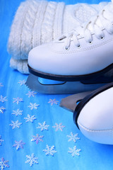 White figure skates and a knitted scarf against the blue background