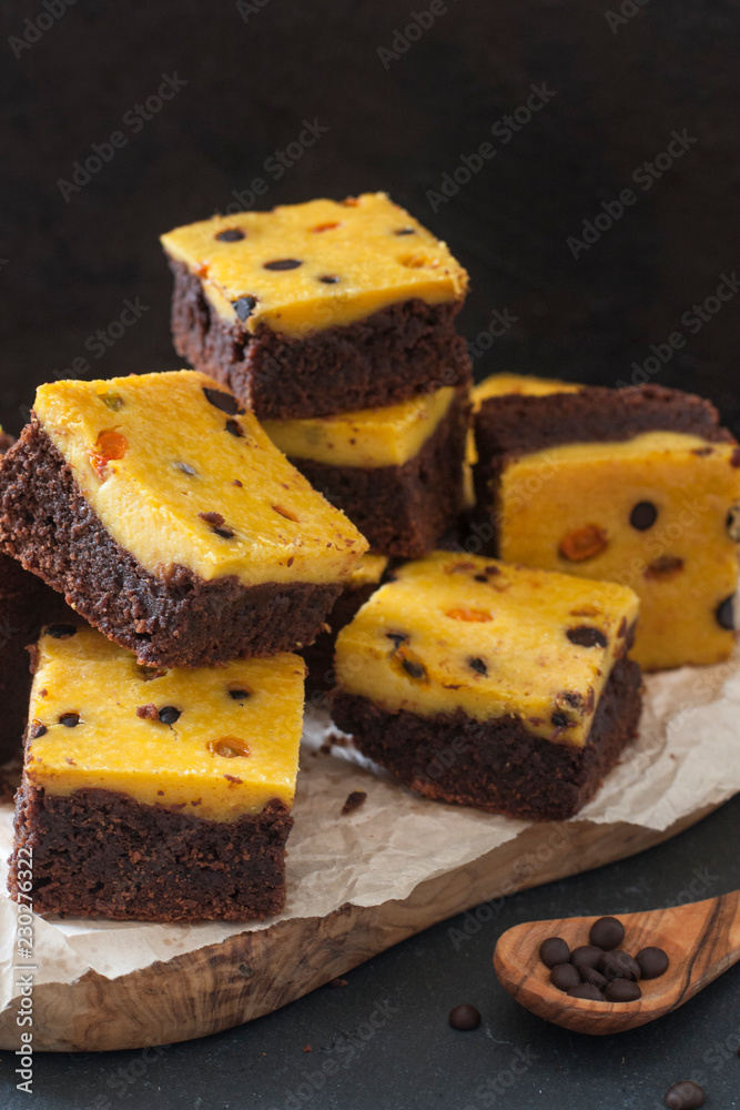 Sticker brownies with cheese cake made from pumpkin, decorated with pease of chocolate and lingonberry