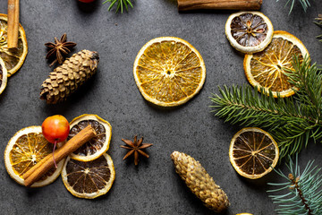 Sliced dried orange with christmas pine branches on dark texture surface. Top view.