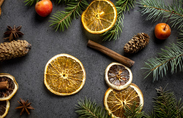 Sliced dried orange with christmas pine branches on dark texture surface. Top view.