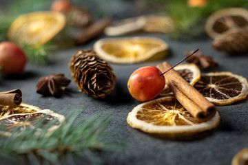Sliced dried orange with christmas pine branches on dark texture surface. Holiday background.
