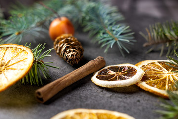 Fototapeta na wymiar Sliced dried orange with christmas pine branches on dark texture surface. Holiday background.