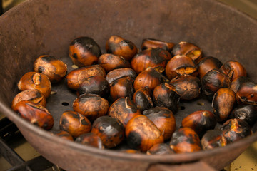 horizontal image with detail of chestnuts cooked in a pan as per the tradition of Italian cuisine