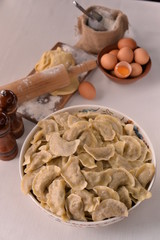 cooked dumplings in bowl and ingredients on white background