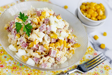 Mixed salad from salami sausage, cheese, boiled egg and canned corn with mayonnaise dressing