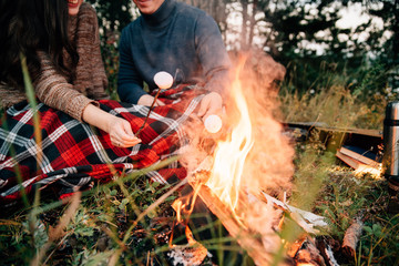 Fototapeta premium Summer Camp Fire. Tourism sexy photo. Cute couple kissing in the park on a sunny day. Adventure concept. Man and woman kissing. Couple in love. Camping fire. Love story. Romance lovers. Fashion photo.