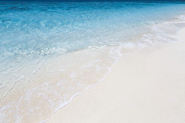 Fototapeta na wymiar Azure clear sea on sandy beach with foam wave, copy space