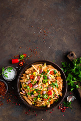 Spicy pasta penne bolognese with vegetables, beans, chili and cheese in tomato sauce