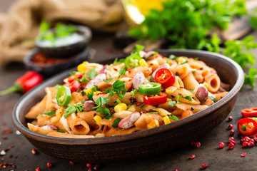 Spicy pasta penne bolognese with vegetables, beans, chili and cheese in tomato sauce