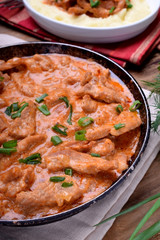 Pieces of meat stewed in tomato and sour cream sauce in the frying pan