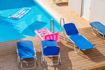 Sunbeds by a swimming pool in sunny day. Vacation, summer and relax.