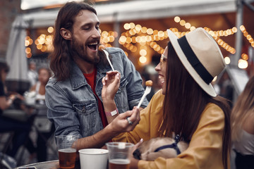 So delicious. Portrait of cheerful girl in hat and bearded guy feeding each other and laughing....