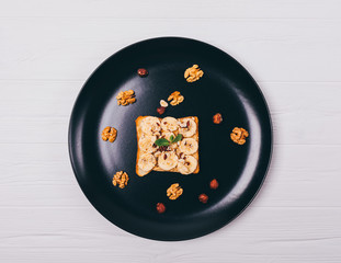 Toast with peanut butter, bananas and nuts on a plate