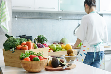 Woman in kitchen with various kind of vegetable and fruits that all are good for health and no meat, vegan lifestyle