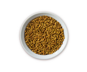 Fenugreek seeds in a wooden bowl isolated on white. Fenugreek seeds isolated on white background. Top view. Fenugreek with copy space for text.