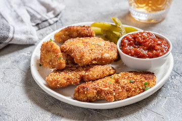 Fried crispy chicken nuggets with ketchup and pickles