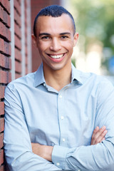 smiling north african businessman leaning on wall outdoors