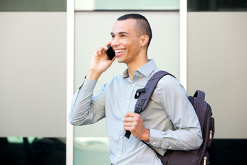 happy young businessman walking and talking on mobile phone