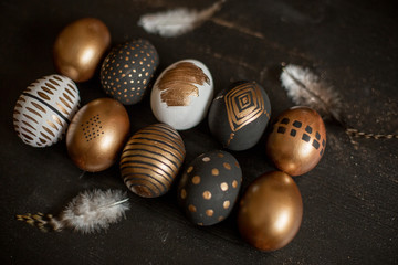 golden decorated easter eggs and black wooden background