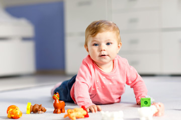 Adorable baby girl playing with domestic toy pets like cow, horse, sheep, dog and wild animals like giraffe, elephant and monkey. Happy healthy child having fun with colorful different toys at home