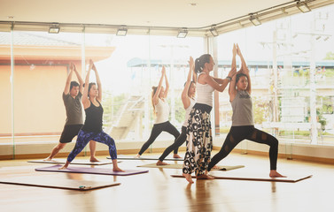 Fototapeta na wymiar Yoga master walk among students and correct pose in a yoga class