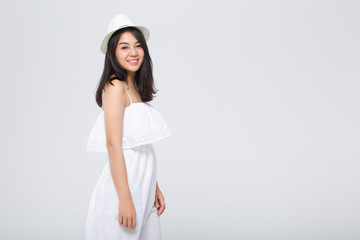 Beautiful young woman in white summer dress,sun hat is standing, looking away and smiling on white background.