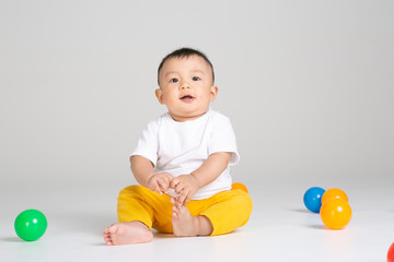 funny baby boy sitting on white background with ball