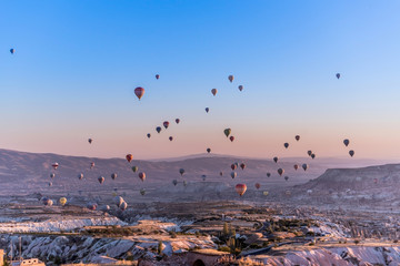 View of hundred of hot air balloons flying all over Cappadocia region from the highest point in Uchisar during the sunrise in the morning, Turkey