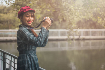 pretty cool young Asian woman with retro film camera or mirrorless camera in modern garden park
