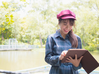 Asian woman relax use tablet to play the Internet to play in the park.