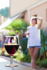 glass of chilled white wine on table over young woman and Bardolino backgound