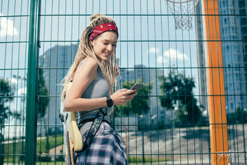 Beautiful lady with dreadlocks smiling and looking at smartphone