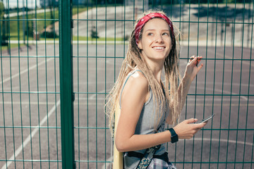 Relaxed woman touching the chain link fence and looking at the beautiful sky