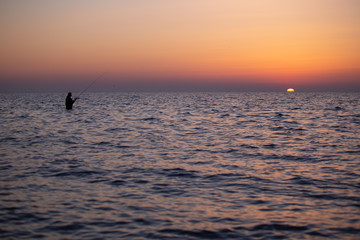 Angler Fischer im Wasser bei Sonnenuntergang