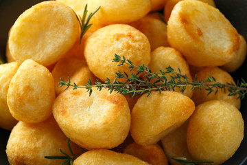 Roast golden potatoes seasoned with salt, garlic, rosemary and thyme on rustic wooden background