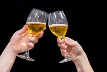 Two friends toasting with glasses of beer at the pub. Black isolated background.