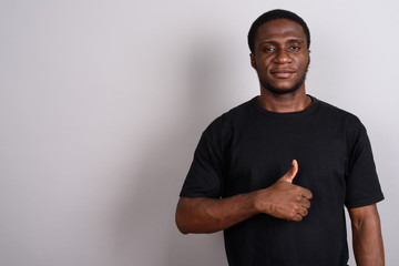 Young African man wearing black shirt against gray background