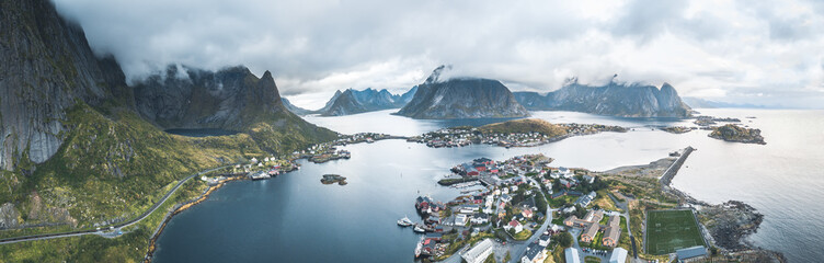 Aerial drone panoramic view of Reine traditional fishing village in the Lofoten archipelago in northen Norway with blue sea and mountains during sunny arctic summer - obrazy, fototapety, plakaty