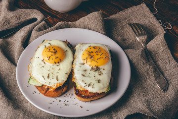 Italian toasts with vegetables and fried eggs on white plate and