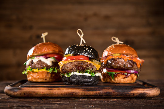 Tasty burgers on wooden table.