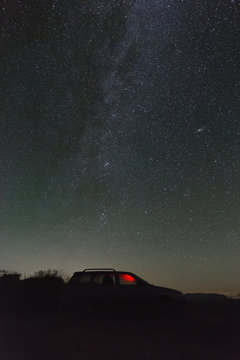 Bright stars of the Milky Way in the night sky over a parked car.