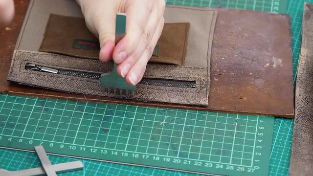 craftsman punches leather edge of inner pocket  by stitching punch