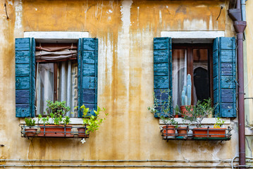 windows with flowers on an old facade in Italy