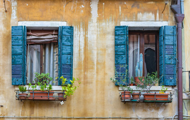 Fototapeta na wymiar windows with flowers on an old facade in Italy