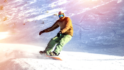Snowboarder on snowboard  piste running downhill in beautiful Alpine landscape rides through snow,...