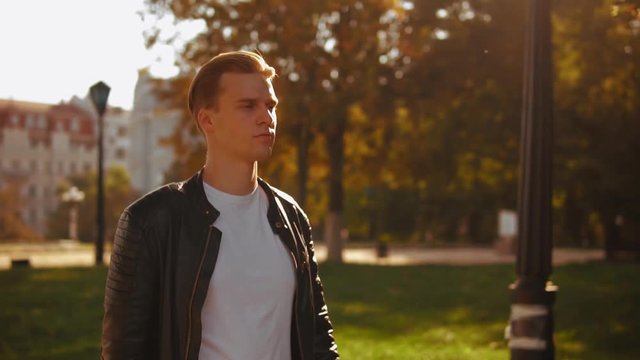 portrait young businessman walking on the street. handsome caucasian guy wearing trendy casual jacket outdoors slow motion