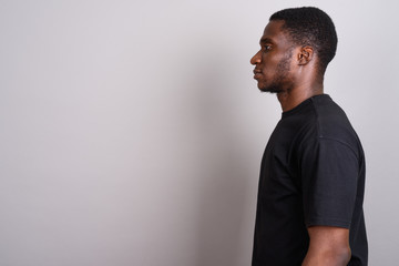 Young African man wearing black shirt against gray background